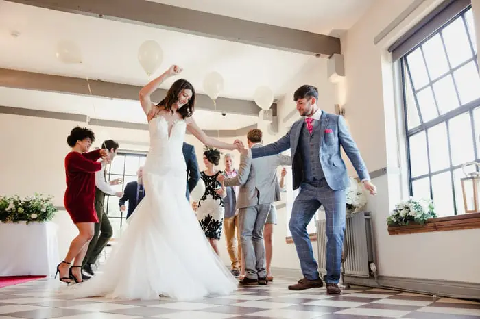A couple and their guests dances at the couple's wedding.