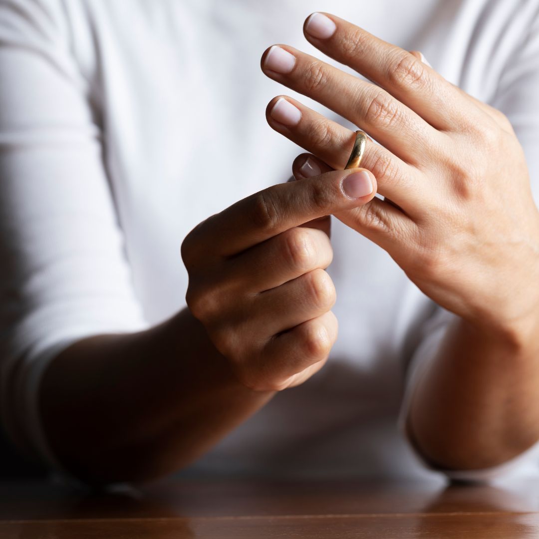 hand removing wedding ring from finger